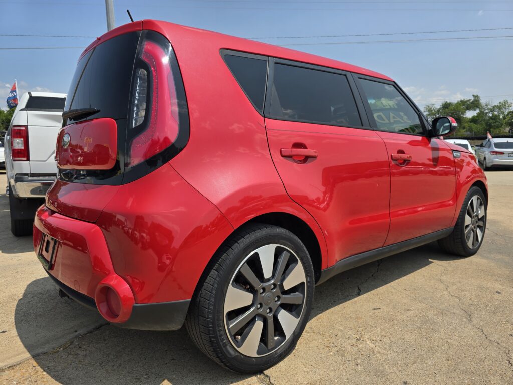 Red SUV parked in a dealership lot, showing the rear and side with large black-tinted windows and stylish alloy wheels
