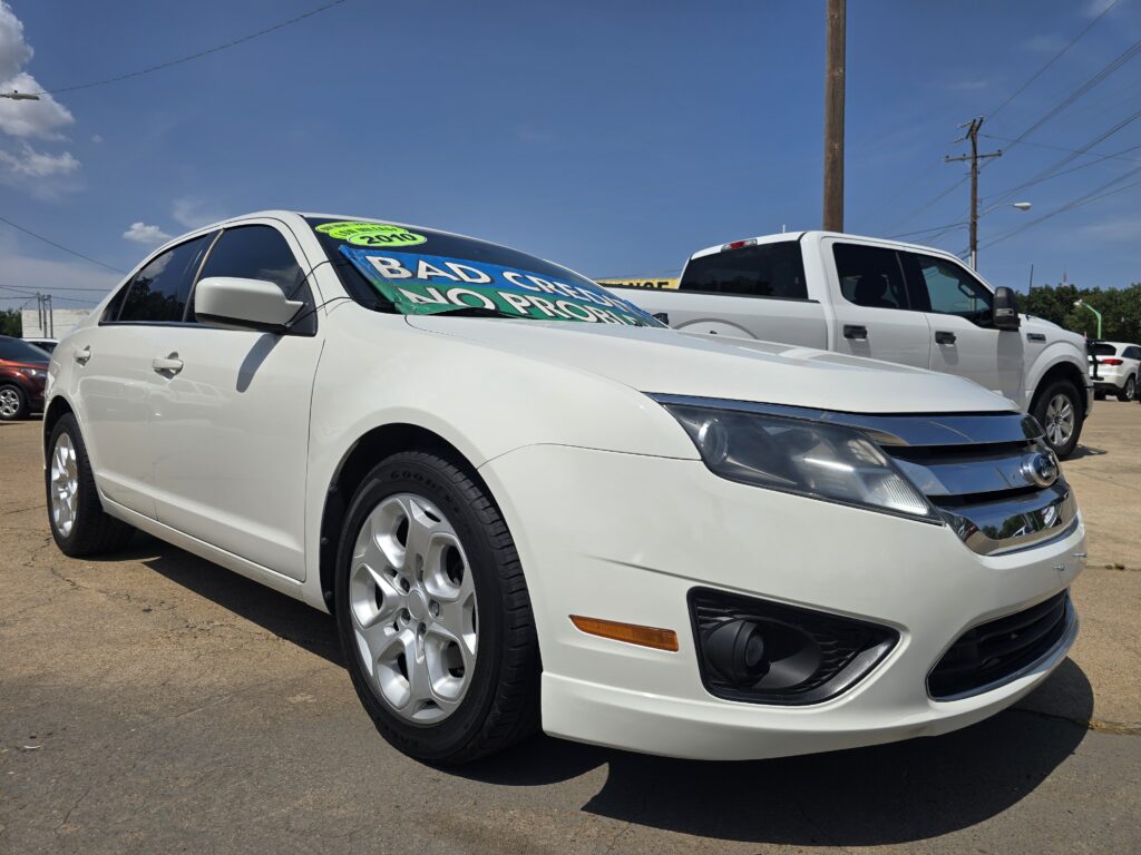 Front of a white SUV with a bright green sale sign on the windshield, parked in a car dealership lot with other vehicles nearby.