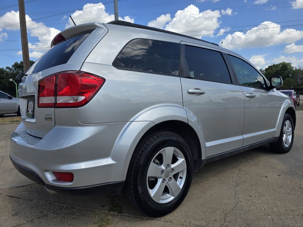 Silver SUV photographed from a rear-side angle in a parking lot, with tinted rear windows and chrome door handles.