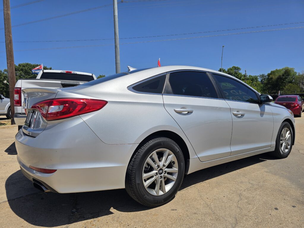 Silver Hyundai sedan in a car lot with other vehicles and a blue sky in the background.