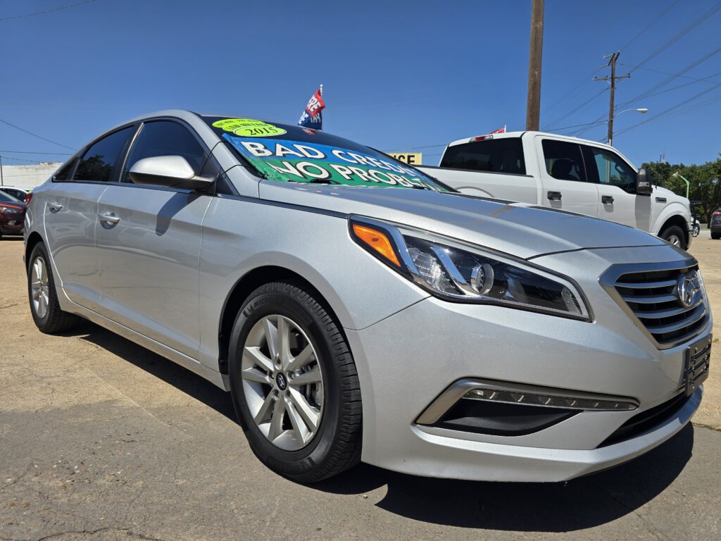 Silver sedan at a used-car lot with a neon green windshield sign displaying the year 2013.