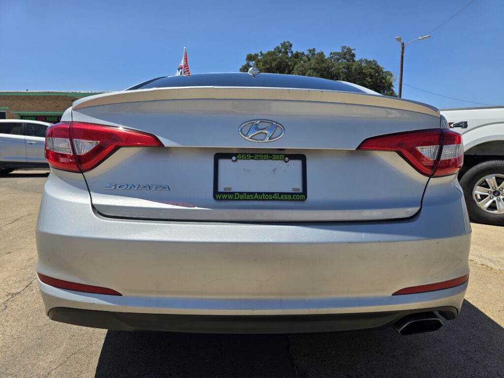 Rear view of a silver Hyundai Sonata with a green dealership plate frame reading Dallas Autos 4 Less