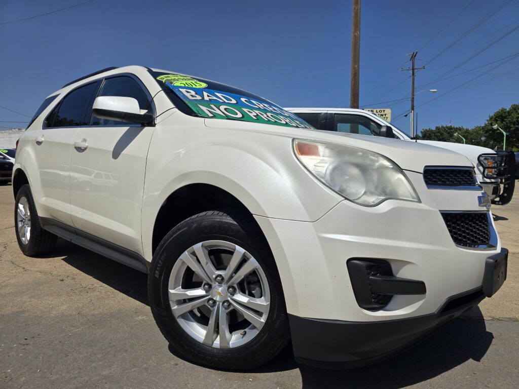 White SUV on a dealership lot with a large green-blue sale banner on the windshield reading 'BAD CREDIT NO PROBLEM'.