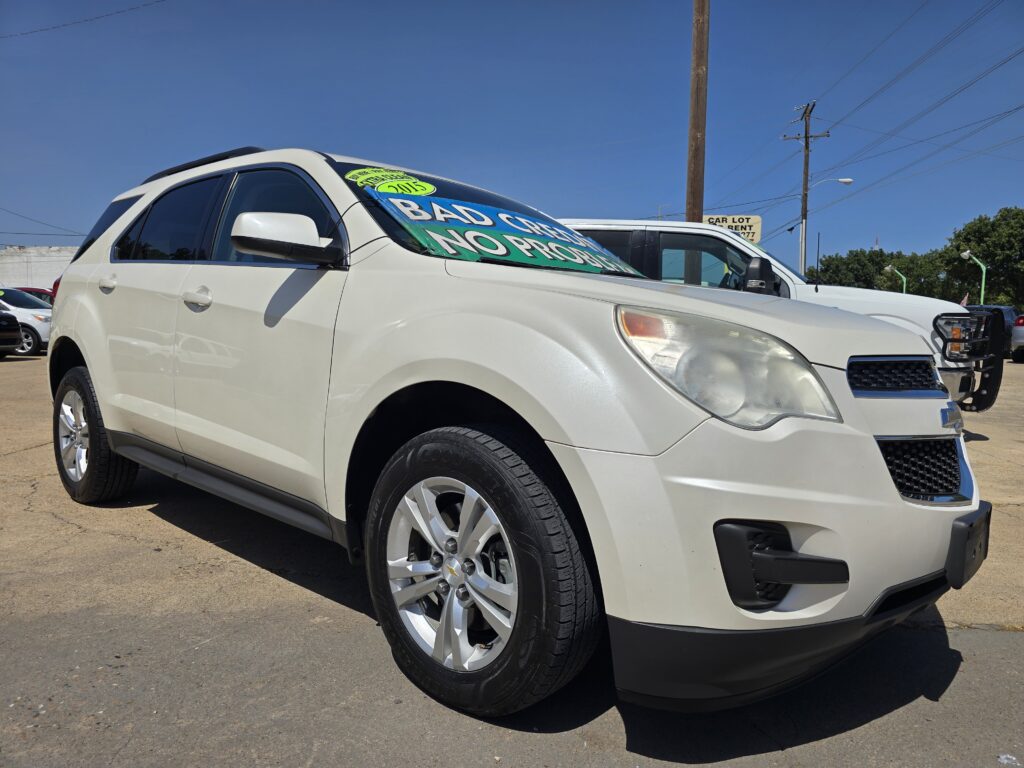 White SUV on a car lot with a large green sign on the windshield reading 'BAD CAR NO PROBLEM' (or similar) and other vehicles in the background.