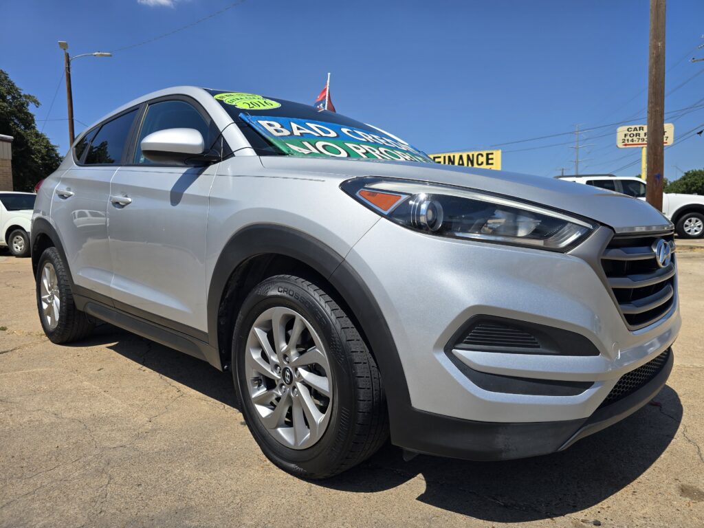 Silver Hyundai SUV in a car lot with large green and white windshield signs reading 'BAD CREDIT' and 'NO PROOF' (informative image).