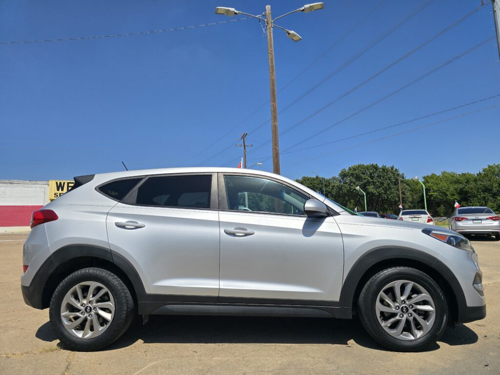 Side view of a silver SUV parked in a lot with a blue sky and utility poles in the background