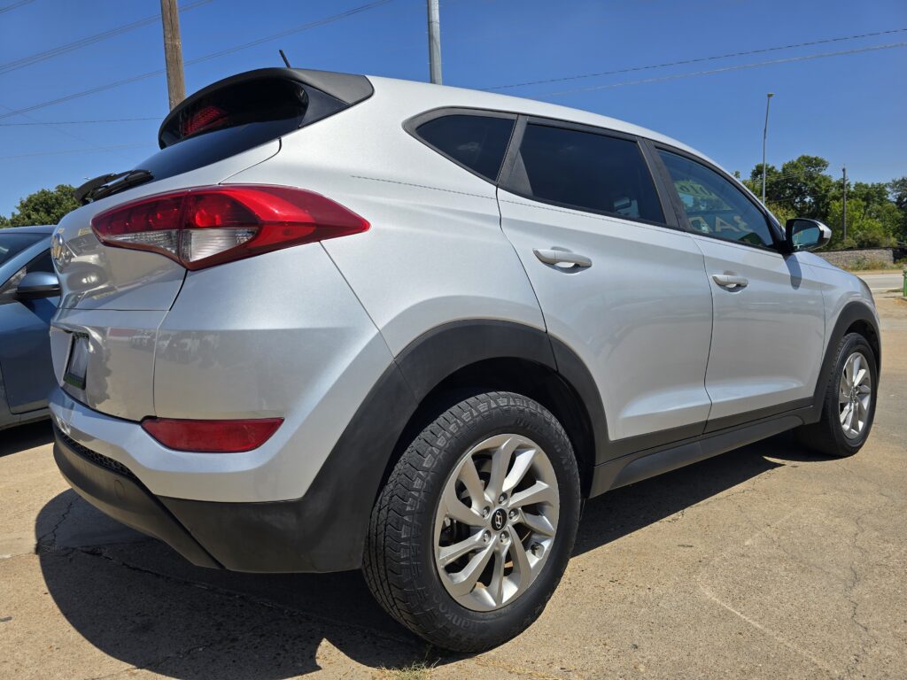 Silver SUV parked on a sunny lot, showing the rear and passenger side with tinted windows and alloy wheels