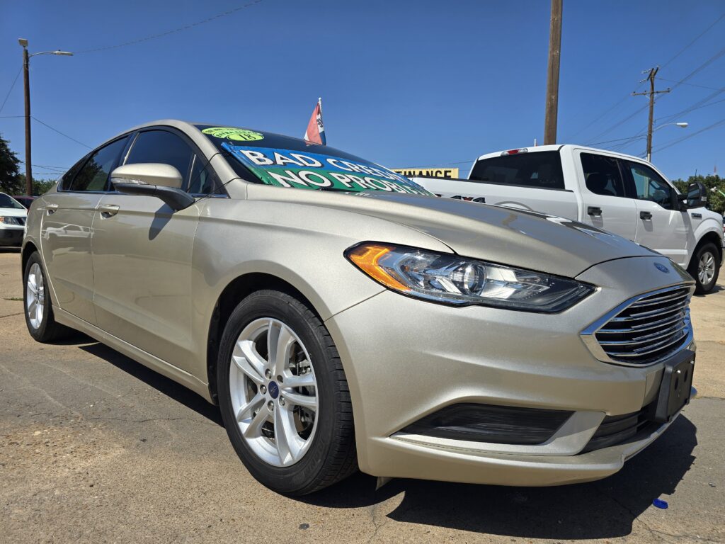 Beige sedan in a parking lot with a large green 'BAD CAR' sign on the windshield.